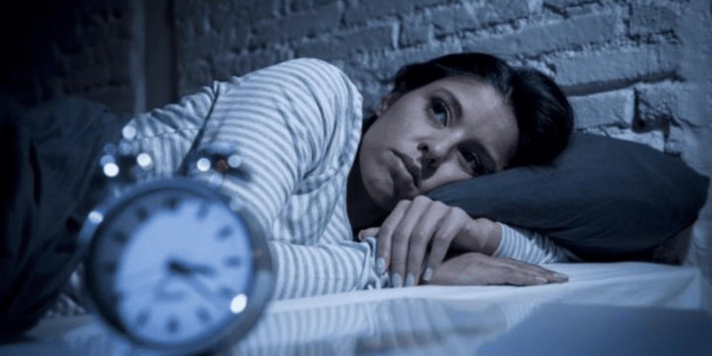 A women staring at the clock unable to sleep.