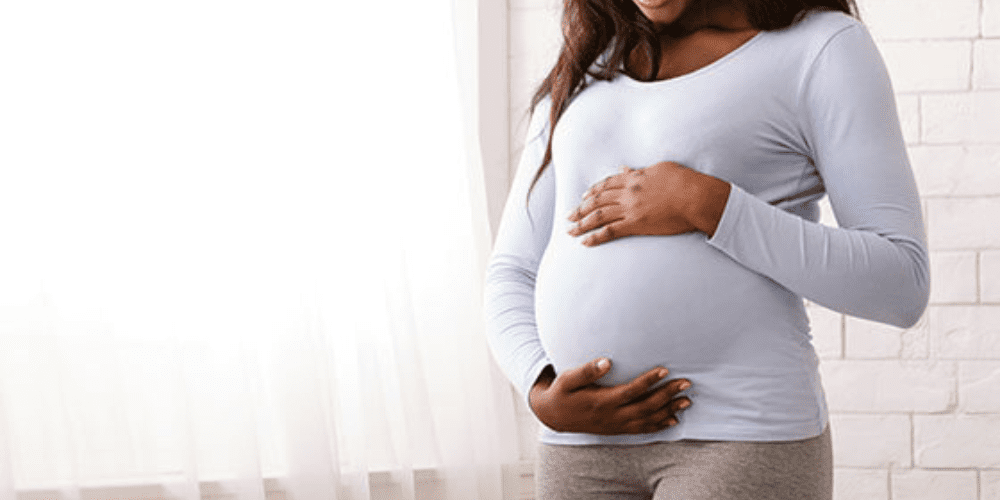 A pregnant women caressing her stomach.